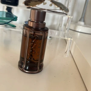 Hugo Boss The Scent Absolute EdP - Hugo Boss The Scent Absolute Eau de Parfum i en stilren, mörkbrun glasflaska med metalliska bronsdetaljer. Flaskan rymmer 50 ml och har en robust, maskulin design med tydlig BOSS-logga i relief. Perfekt för dig som gillar eleganta och moderna dofter.