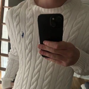 Ralph Lauren Kabelstickad - Vit kabelstickad tröja från Polo Ralph Lauren. Tröjan har rund halsringning, ribbade muddar och är långärmad. Perfekt för hösten! Köpt ifrån Åhléns Sthlm, för 2395kr. Utmärkt skick - använd endast nån gång då den ej passar mig riktigt! Kvitto finns via Kivra om önskas.