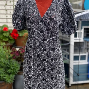 Svart broderad klänning Costes Atelier L - Svart omlottklänning med foder och ett paisley-liknande mönster i vitt. Klänningen har en V-ringning och puffärmar. 100% bomull Längd: 88 cm Bystvidd: 50 cm. Katter finns i hemmet! 01,S