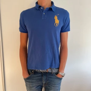 Blå Polo Ralph Lauren Piké - Tjena! Säljer denna feta piké från Polo Ralph Lauren. Den har en stor gul broderad logga på bröstet och siffran 3 på ärmen. Tillverkad i mjuk bomull! Tveka inte på att höra av dig ifall du har några frågor! 🙌Priset är inte hugget i sten! 🪨 