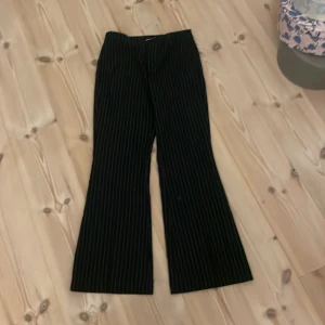 Svarta randiga kostymbyxor Gina Tricot - Mörk blåa kostymbyxor från Gina Tricot i storlek 36 med smala vita ränder. Byxorna är bootcut  