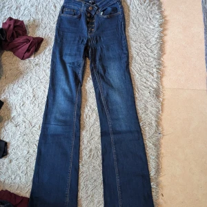 Mörkblå bootcut jeans - Snygga mörkblå jeans med hög midja och bootcut-ben. Jeansen har flera knappar framtill istället för dragkedja och klassiska fickor både fram och bak. Det där stretchiga bitarna syns knappt när de är på.☺️