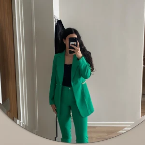 Grön kostymset - Säljer en snygg grön kostym från Miss Frendy i storlek 40, skulle säga att de är mindre i storlek så mer en S/M. Kavajen har guldiga kedjedetaljer vid fickorna och en enkel knäppning framtill. Byxorna är raka och höga i midjan. Perfekt för dig som vill sticka ut med färg och stil. Kavajen är använd endast 1 gång medan byxorna är aldrig använda 