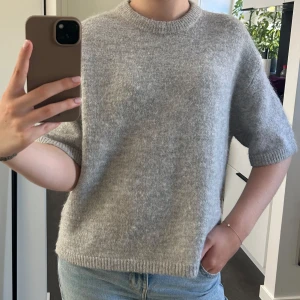 Grå stickad tröja från Gina Tricot - Mysig grå stickad tröja från Gina Tricot ”premium quality”.  Med kort ärm och rund halsringning. Tröjan har en rak, lite boxig passform och ribbade kanter vid ärmslut och nederkant. Perfekt för lager-på-lager och chill dagar inför hösten!🤎🤎🤎