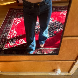  blå jeans  - Säljer ett par klassiska jeans i mörkblå denim. Byxorna har mid midja, raka ben med lätt bootcut och femficksmodell. Snygga kontrastsömmar och robust bomullsmaterial. Perfekta för dig som gillar en tidlös och avslappnad look.