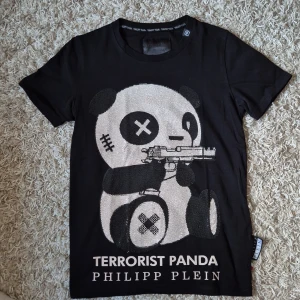 Svart t-shirt terrorist panda Philipp Plein Nyskick  - Cool svart t-shirt  med ett stort glittrigt panda-motiv på framsidan och texten 'Terrorist Panda'. Klassisk passform och korta ärmar. Märkesdetaljer på både etikett och baksida. Perfekt för dig som gillar statement-plagg. S/M