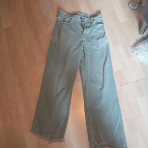 Gråa wide jeans med råa kanter - Säljer ett par gråa jeans från Only i modell med breda ben och råa, fransiga benslut. Jeansen har klassisk femficksdesign och stängs med dragkedja och knapp. Perfekta för dig som gillar en avslappnad och trendig look.