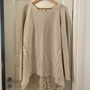 Beige stickad kofta från ADME - Beige lång stickad kofta från ADME i storlek L. Koftan har snygga knappar back, lång ärm och dekorativa stickade detaljer längs sidorna. Perfekt för lager-på-lager och chill stil under höst och vinter.