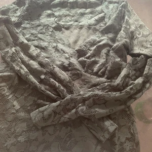 Svart spetstopp från Yessica - Supersnygg svart spetstopp från Yessica. Toppen har ett elegant spetsmönster och är perfekt för dig som vill sticka ut lite extra. Den har långa ärmar och v-ringad hals. Perfekt för dig som gillar en feminin och trendig stil.