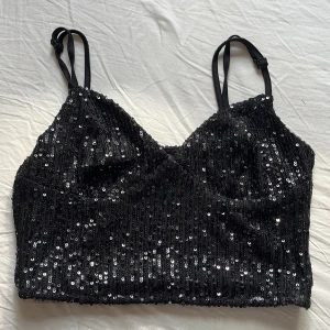Svart paljettopp - Säljer nu en svart croppad topp täckt med glittrande paljetter. Toppen har smala, justerbara axelband och en figurnära passform. Perfekt för dig som vill sticka ut med en snygg och glammig look. Materialet är mjukt på insidan för extra komfort 🖤