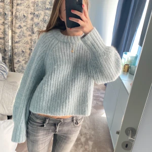 Ljusblå stickad tröja från H&M - Supermysig ljusblå stickad tröja från H&M i alpackablandning. Tröjan har en loose passform, bred ribbad struktur och långa ärmar med extra långa muddar. 