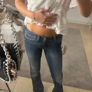 Blå bootcut jeans från weekday - Snygga blå jeans från weekday med bootcut passform och låg midja. Jeansen har klassisk femficksdesign, och en grön weekday-logga på bakfickan. Tillverkade i jeansmaterial som sitter skönt och ger en avslappnad vibe.