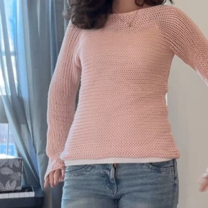 Ljusrosa stickad tröja - Säljer en ljusrosa stickad tröja med lång ärm och rund hals. Tröjan har en luftig, virkad känsla och är perfekt för lager-på lager!