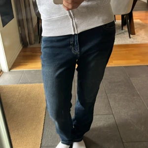 Mörkblå raka jeans med kontrastsömmar - Säljer ett par mörkblå jeans med raka ben och snygga kontrastsömmar. Jeansen har klassiska bakfickor med dekorativ söm och normal passform. Aldrig använda!