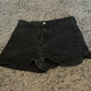 Svarta högmidjade jeansshorts &Denim - Svarta stretchiga jeansshorts från &Denim i högmidjad modell. Klassisk femficksdesign med knapp och dragkedja framtill. Snygg rå kant nedtill och mjukt denimtyg som sitter bekvämt. Perfekt för dig som gillar en enkel och cool stil.