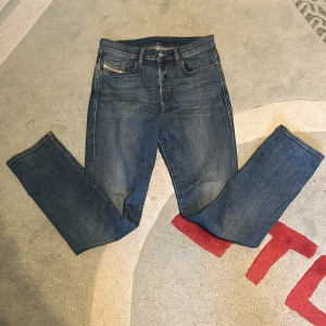 Blå jeansbyxor från Diesel - Snygga blå jeansbyxor från Diesel med klassisk femficksdesign och raka ben. Jeansen har en normal passform och är tillverkade i slitstarkt denimtyg. Perfekta för dig som gillar en tidlös och avslappnad stil.
