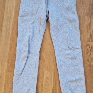 Grå mjukisbyxor Peak Performance XS - Ljusgrå mjukisbyxor från Peak Performance med broderad logga och ribbad midja. Byxorna har en klassisk passform med dragsko i midjan och är tillverkade i mjuk bomullsmix. Perfekta för chill eller träning.