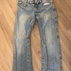 Ljusblå jeans från Perfect Jeans, Gina tricot - Säljer ett par ljusblå jeans från Perfect Jeans med snygg tvätt och raka ben. Byxorna har klassiska fem fickor, coola bakfickor med knapp och dubbla knappar i midjan. Perfekta för dig som gillar en avslappnad och trendig look.