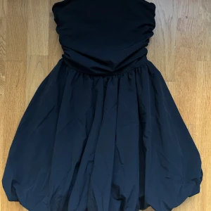 Svart axelbandslös kortklänning - Supersnygg svart bandeau ballongklännig med resår i ryggen. Använd ett fåtal gånger!! Går att förhandla!!🥰