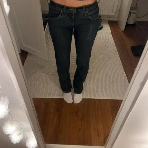 Mörkblå Lee jeans straight fit - Säljer ett par mörkblå lågmidjade jeans från Lee med klassisk femficksdesign och raka ben. Jeansen har normal passform och är tillverkade i slitstarkt denimtyg med snygga kontrastsömmar och läderpatch med Lee-logga bak i midjan. 