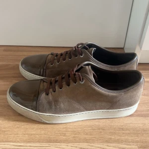 Bruna sneakers från Lanvin i mocka  - Skorna är i väldigt bra skick och har en glänsande cap toe. Storlek 43–44 (passar lite olika fotstorlekar). Använda men inte på ett bra tag, ser fortfarande nästan nya ut. Nypris: ca 5000 kr. Mitt pris: 1600 kr – kan diskuteras vid snabb affär. Vid fler frågor är det bara att fråga!