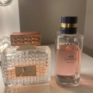 Två parfymer: Coeur Rivoile & La Rive - Säljer två parfymer för kvinnor. Coeur Rivoile har en genomskinlig flaska med hjärtmönster och roséguldfärgat lock, medan La Rive Her Choice kommer i en stilren, rektangulär flaska med rosa vätska och mörkblått lock med gulddetalj. cœuer är ca 40% kvar och La rive är ca 80% kvar (se bild)💌 (100 kr för båda eller 65kr/st) 