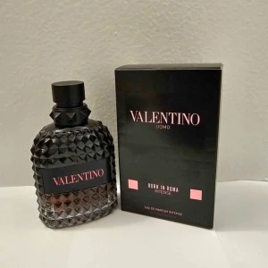Valentino Uomo Born In Roma Intense - Säljer en lyxig herrparfym, Valentino Uomo Born In Roma Intense. Flaskan är svart med nitar och har en modern, edgy design. Kommer i originalkartong med rosa detaljer och text. Eau de Parfum med intensiv doftprofil.