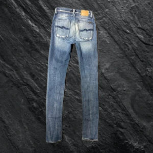 Nudie Jeans med nice slitning - Nudie Jeans med nice fading/slitning på baksidan. Storlek 27,  längd 34. Sitter som 28. Sitter perfekt med en nice stack, mina favorit jeans. Skriv om ni har frågor!
