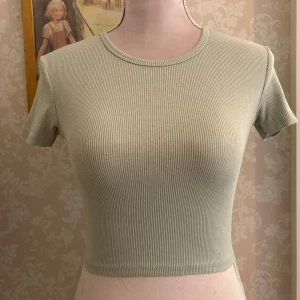 Ljusgrön ribbad baby-tee från Pull&Bear - En så snygg ljusgrön baby-tee från Pull&Bear i storlek S. Toppen är ribbad med korta ärmar och rund halsringning. Perfekt basplagg.