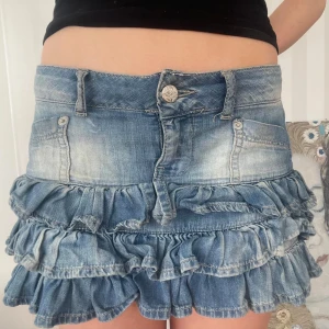 Blå jeanskjol med volanger - Snygg vintage lågmidjad jeanskjol. Midjemått 40, längd 30
