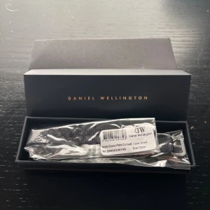 Svart klockarmband Daniel Wellington - Snyggt svart klockarmband från Daniel Wellington, modell Classic Petite Cornwall. Armbandet är 12 mm brett och har ett silverfärgat spänne.