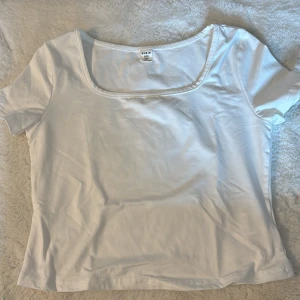 Vit topp med fyrkantig ringning Shein - Enkel och stilren vit topp från Shein med korta ärmar och snygg fyrkantig ringning. Tillverkad i mjuk bomull, perfekt för att matcha med jeans eller kjol. Klassisk modell som funkar året runt.