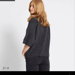 Mörkgrå stickad tröja med vida ärmar - Mysig mörkgrå stickad tröja med rund hals och trekvartsärmar. Tröjan har en loose passform och är perfekt för lager-på-lager. Enkel och stilren design som funkar till det mesta.