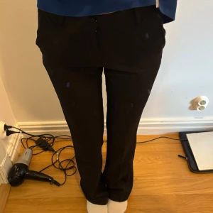 Svarta kostymbyxor från BikBok - Snygga svarta lowwaist kostymbyxor från BikBok i storlek 34, modell Vera tall. Byxorna har raka ben, lite flare, bälteshällor och klassisk passform. Långa!! jag är 175, använda ett fåtal gånger💞