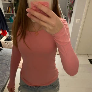 Rosa långärmad topp från 157 - Säljer en enkel och snygg rosa långärmad topp från lager 157 i storlek S. Toppen är figurnära med rund halsringning och är gjord i mjuk bomull med lite stretch för en bekväm passform. Perfekt att matcha med jeans eller kjol för en chill look. Helt oanvänt med lappen kvar. 