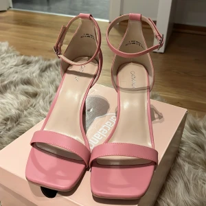 Rosa klackade sandaler från Catwalk - Snygga rosa sandaler med smal rem över tårna och runt vristen, fyrkantig tå och medelhög klack. Skorna har en stilren design och är gjorda i syntetmaterial. Perfekta för dig som vill ha en poppig färg på fötterna. Dessa är också helt oanvända och jag har varit latt  med altt lämna tbx det eftersom storleken ej passat men dem är i ett helt ny kick! Priset på dessa där jag köpte dem var 499! 