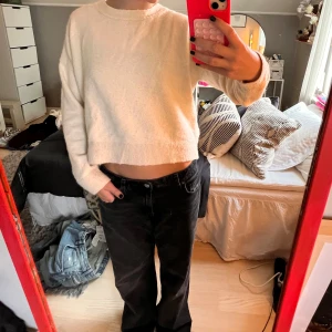 Ljusbeige croppad stickad tröja med rosett - Superfin ljusbeige stickad tröja med croppad passform och lång ärm. Baksidan har en snygg detalj med en rosett i nacken som ger en extra touch. Perfekt för dig som gillar mjuka material och stilrena plagg.