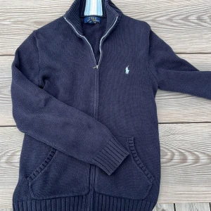 Polo Ralph Lauren stickad - Hej, jag säljer en stickad ralph lauren tröja i färgen marinblå. Köpte den på kids brand store för 10 månader men har inte använt den så mycket. Sista bilden är från kidsbrand store