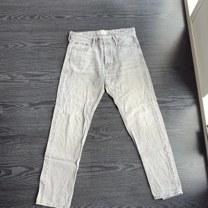 Ljusgrå jeans från Jack & Jones - Snygga ljusgrå jeans från Jack & Jones med klassisk femficksdesign och raka ben. Jeansen är i modellen loose/chris och storleken är 30/32 