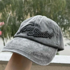 Grå keps från Acne Studios - Snygg grå keps från Acne Studios med broderad logga framtill i svart. Kepsen har en tvättad vintage-look och böjd skärm. Justerbar rem baktill för perfekt passform. Perfekt accessoar för en cool och avslappnad stil.