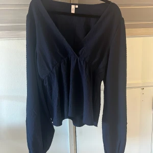 Marinblå blus med v-ringning från Nelly - Supersnygg marinblå blus från Nelly med v-ringad omlottfront och långa ärmar. Blusen är helt oanvänd och är super fin!  