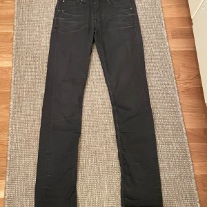 Svarta Tiger Of Sweden - Svarta jeans med skinny fit och klassisk femficksdesign. Byxorna har smala ben och normal midja, perfekta för en clean och stilren look. Materialet är stretchigt jeans, vilket gör dem bekväma att bära hela dagen.