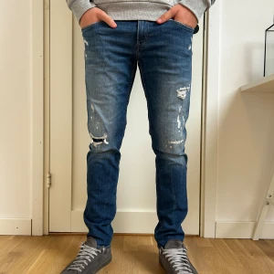 Replay Anbass slim fit 29/30 - Säljer ett par blå jeans slim fit med slitna detaljer på benen.  Jeansen har klassisk femficksdesign, normal midja och är tillverkade i stretchig bomullsdenim för skön känsla. Perfekta för dig som gillar en trendig och avslappnad look. Storlek W29L30 Ny pris 2100kr
