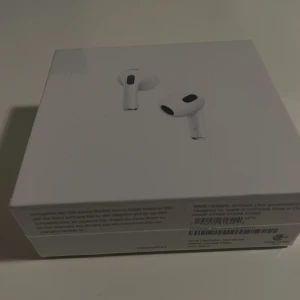 AirPods (3rd generation) med MagSafe-laddningsetui - Helt nya Apple AirPods (3rd generation) med MagSafe-laddningsetui, oöppnad originalförpackning. Trådlösa hörlurar med förbättrad batteritid, rumsligt ljud och svett-/vattenresistens. Perfekt för musik, samtal och träning. Ingen synlig skada på förpackningen.