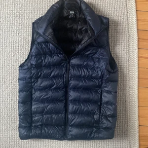 Mörkblå dunväst från Uniqlo XS - Snygg mörkblå dunväst från Uniqlo i storlek XS. Västen är ultralätt, quiltad och har dragkedja framtill. Perfekt för lager-på-lager och har en stilren, enkel design . Vid frågor är det bara att skriva till mig ! Pris 229