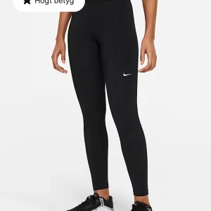 Svarta leggings från Nike - Svarta leggings från Nike med hög midja och diskret logga på låret. Tight passform och meshdetaljer på baksidan av benen för extra ventilation. Perfekta för träning eller chill dagar. Tillverkade i stretchigt syntetmaterial som andas.