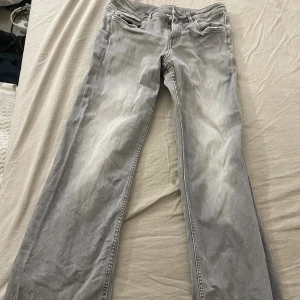 Grå bootcut jeans från Kappahl 170 - Snygga grå jeans från Kappahl i storlek 170. Modellen har bootcut-ben och klassiska fickor med lock bak samt dragkedjor framtill. Jeansen är tillverkade i bomull och har en cool, lite tvättad look.