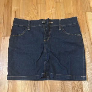 Mörkblå jeanskjol från Flash Jeans - Snygg mörkblå jeanskjol från Flash Jeans med klassisk femficksdesign och dekorativa sömmar på bakfickorna. 