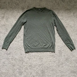 Olivgrön tunn stickad tröja H&M - Snygg olivgrön stickad tröja från H&M med rund halsringning och långa ärmar. Perfekt för lager-på-lager och enkel att matcha med jeans eller chinos. Tunn och mjuk kvalitet som passar året runt.