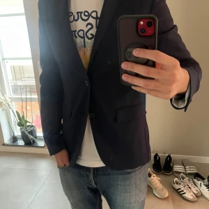 Mörkblå kavaj från Corneliani - Säljer en stilren mörkblå kavaj från CC Collection Corneliani. Klassisk modell med två knappar framtill, fickor med lock och slits bak. Perfekt för dig som vill ha en snygg och tidlös look. Materialet känns mjukt och följsamt. Nypris runt 3499kr mitt pris 949kr